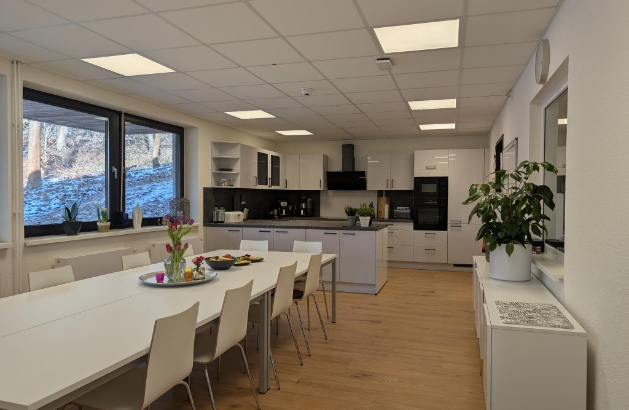 großer Raum mit langem Tisch und Blick in den Wald