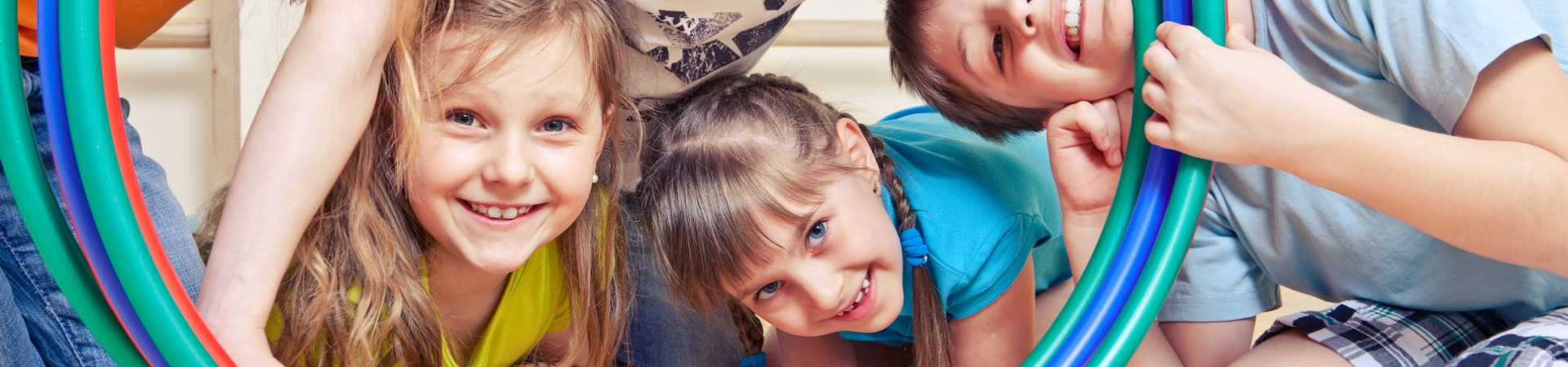Spielende Kinder schauen durch einen Reifen