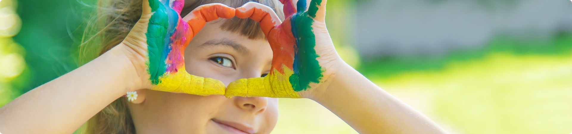Kind mit angemalten Fingern lacht in die Kamera